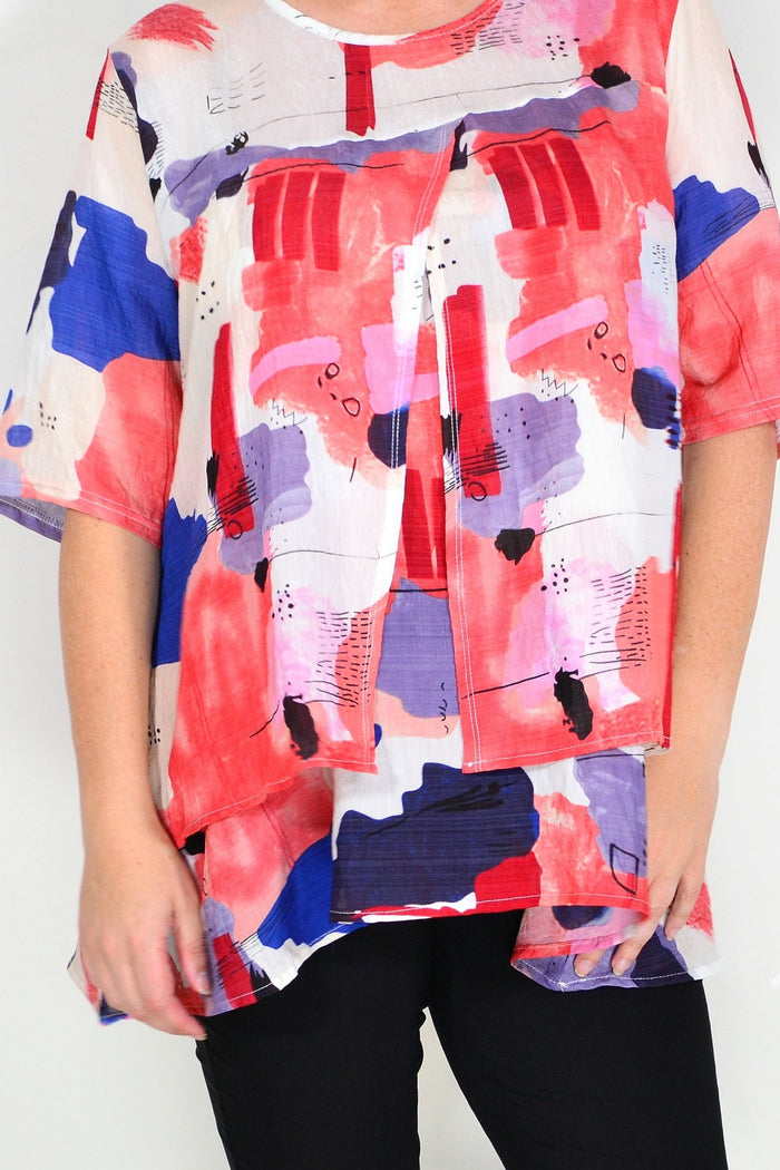 Red layered abstract tunic top by Whispers, showcasing flowy fabric and artistic design on a stylish women's tunic.