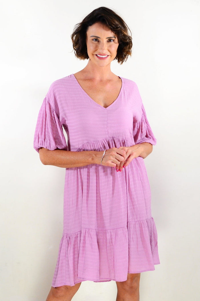 Soft pink tiered tunic dress by Willow Tree, featuring flowing fabric and layered design, displayed on a hanger.