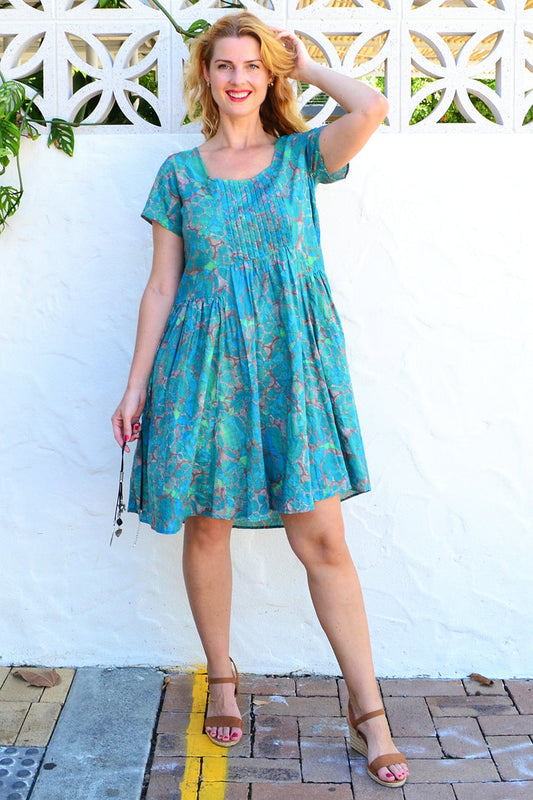 Emerald aqua abstract Wishstone tunic dress with flowing fabric and vibrant pattern, showcased on a hanger.