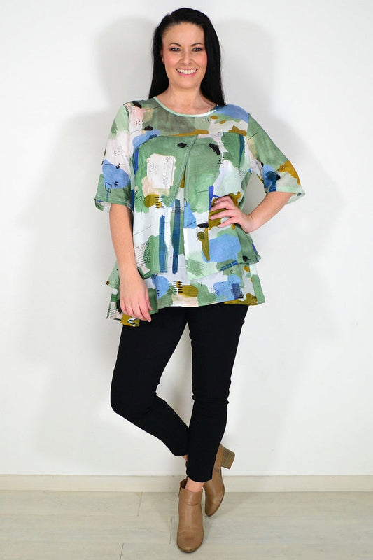 Green layered abstract tunic top by Whispers, featuring flowing fabric and artistic design, displayed on a hanger.