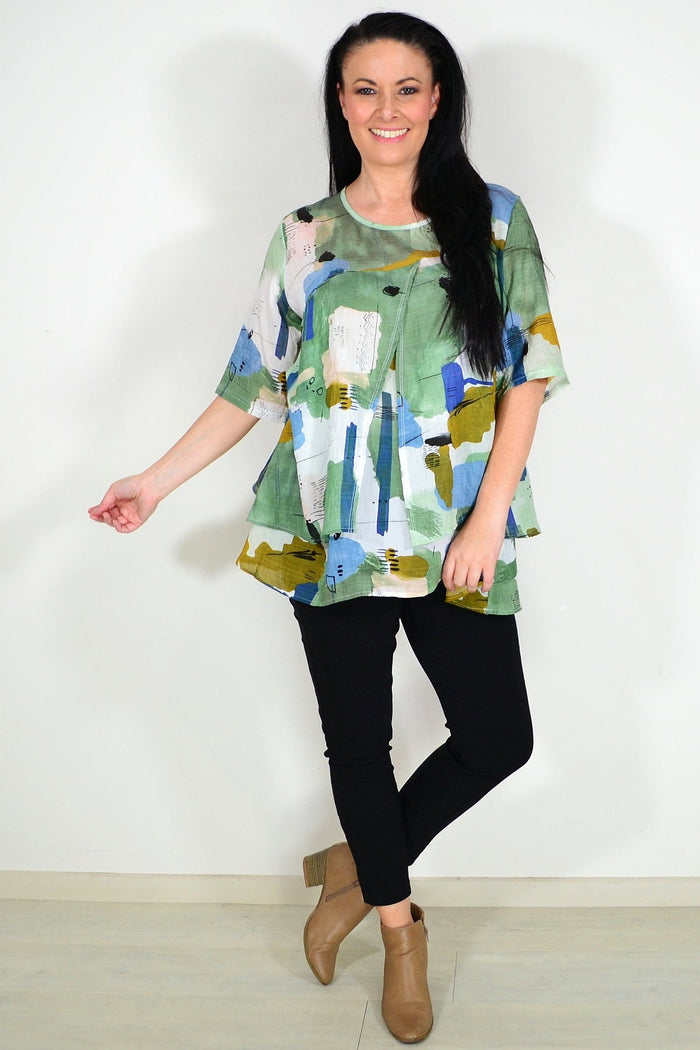 Green layered abstract tunic top by Whispers, featuring flowing fabric and artistic design, displayed on a mannequin.