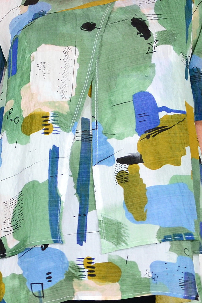 Green layered abstract tunic top by Whispers, featuring a flowing design and artistic print, displayed on a hanger.