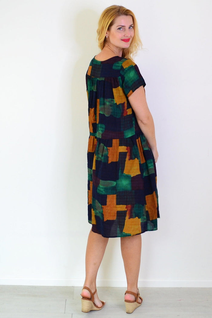 Wishstone mustard olive abstract tunic dress displayed on a hanger, featuring a blend of vibrant colors and stylish design.