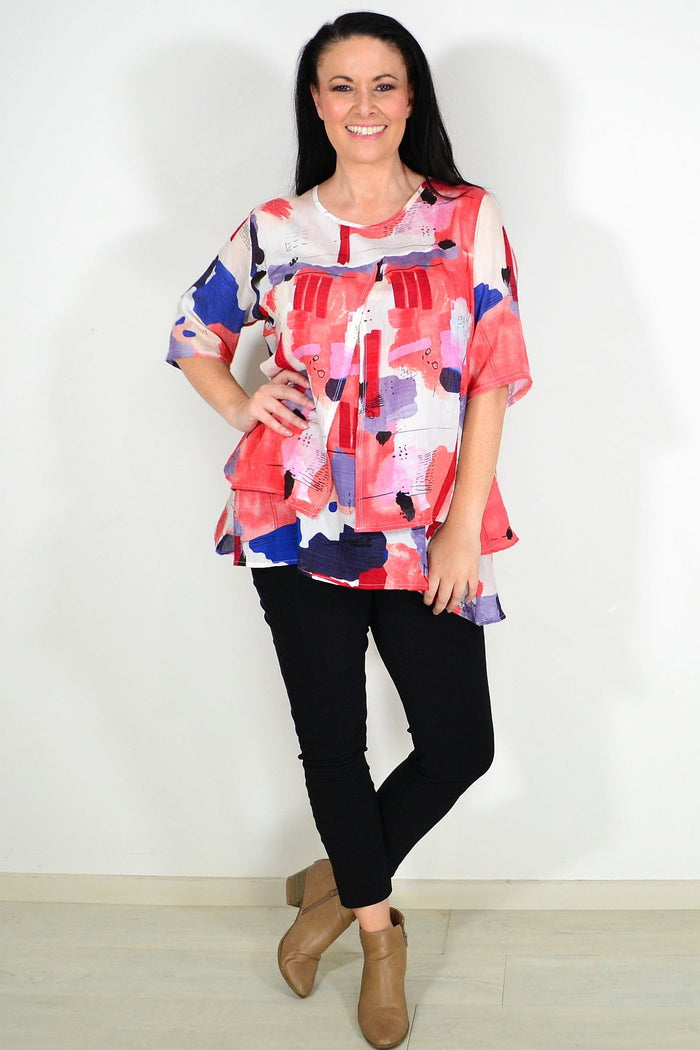 Red layered abstract tunic top by Whispers, featuring flowing fabric and artistic pattern, shown on a model.
