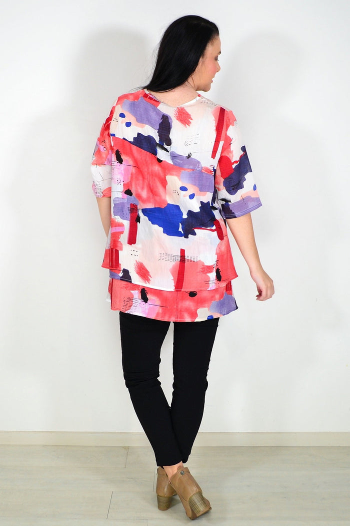 Red layered abstract tunic top by Whispers, featuring flowing fabric and unique artistic design, shown on a model.